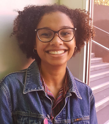 Chloe Austin standing next to a window and smiling into the camera