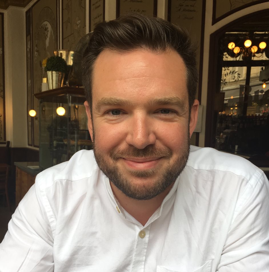 A headshot of James Mansell sitting down and smiling towards the camera.