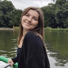 Smiling young white woman with long brown hair in front of a lake