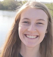 Smiling young white woman outdoors on a sunny day in front of a lake