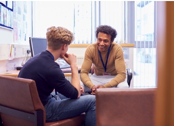 A male student sat talking to a male advisor.