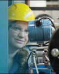 Katy McKenzie in a yellow hard hat working in an engineering lab.