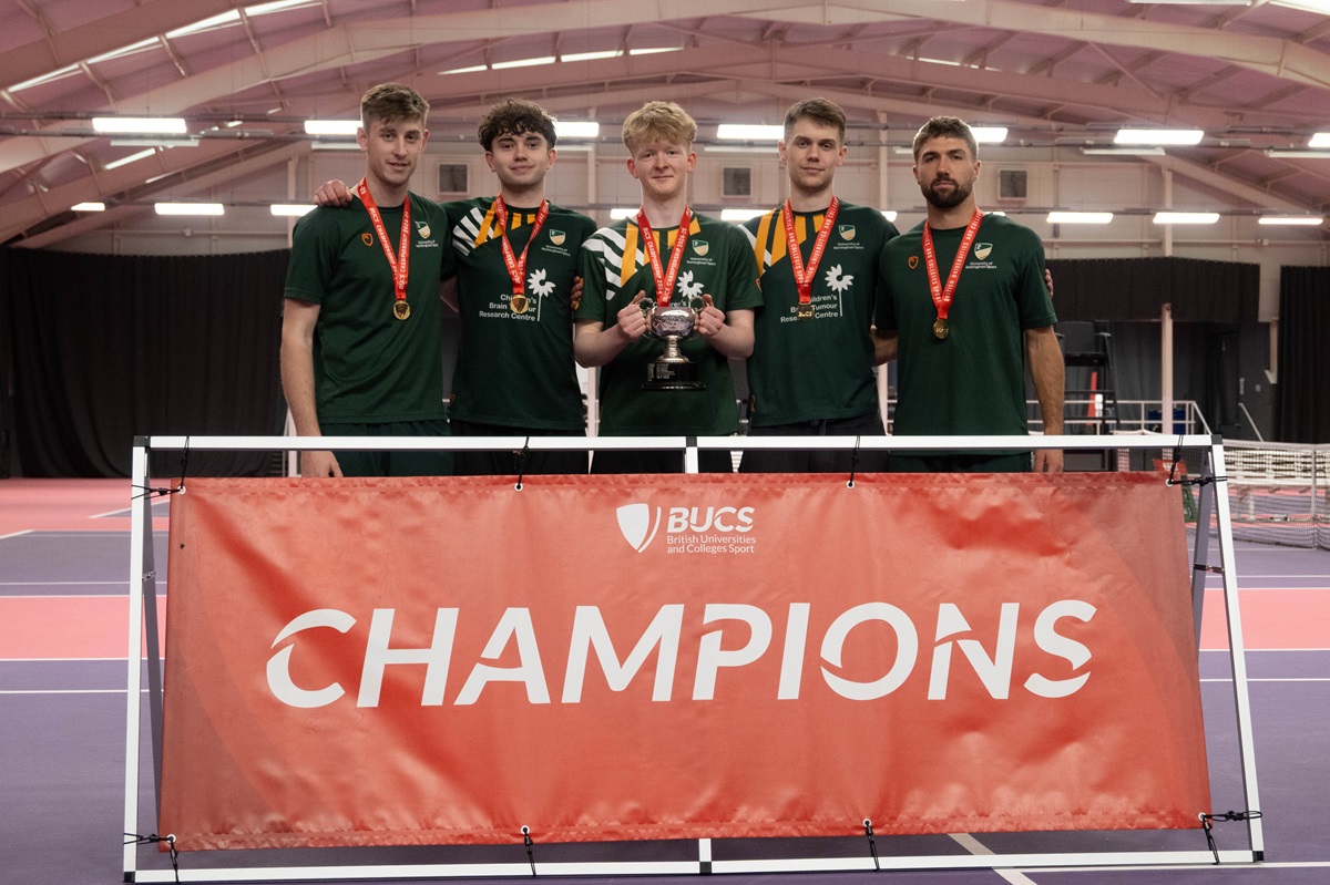 Tennis players hold trophy in front of Champions board
