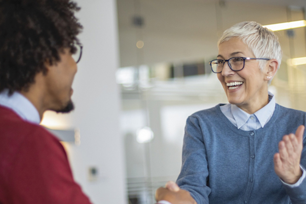 Employer smiling and shaking hand of successful job candidate