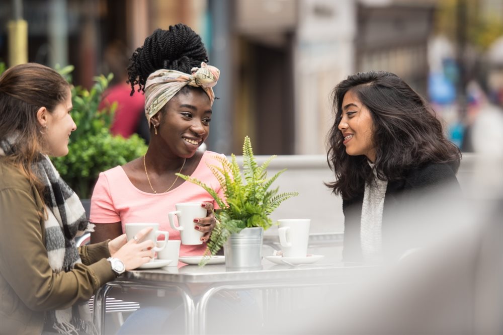 Three students sitting outside cafe talking