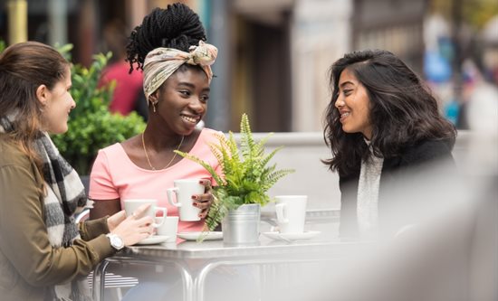 Three students sitting outside a cafe talking