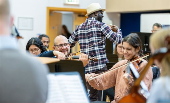 Close up of string section of orchestra rehearsing