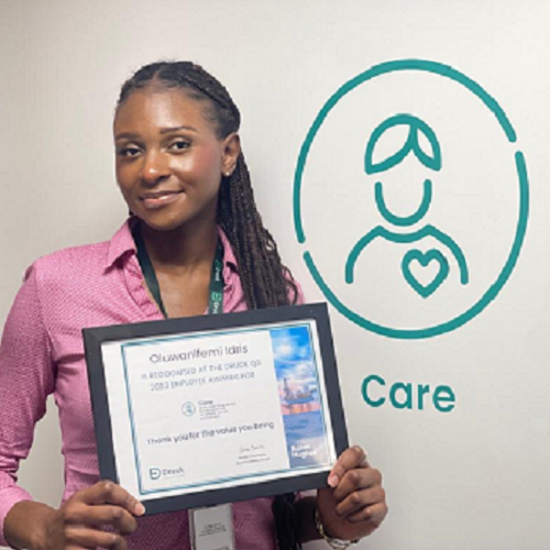 Photo of student Nifemi Idris holding her Care Award. Nifemi is wearing a pink shirt.