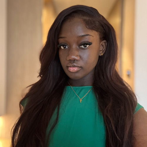 Kirsten Lartey with long dark brown hair and wearing a bright green top and necklace