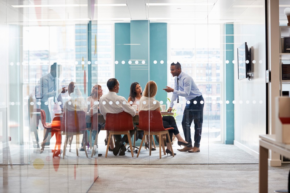 Male standing collaborating with a team.