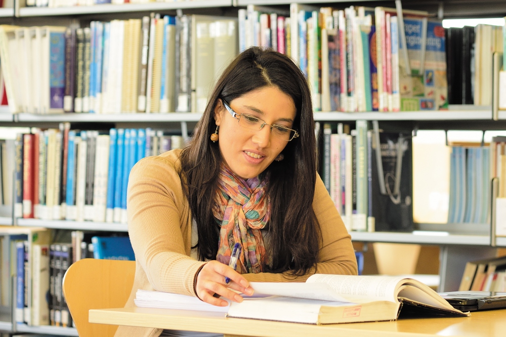 Female sat in a library reading a book