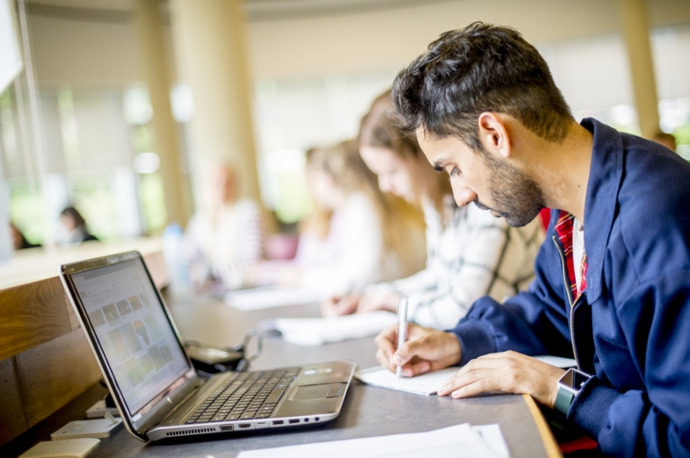 Student writing notes in the George Green Library