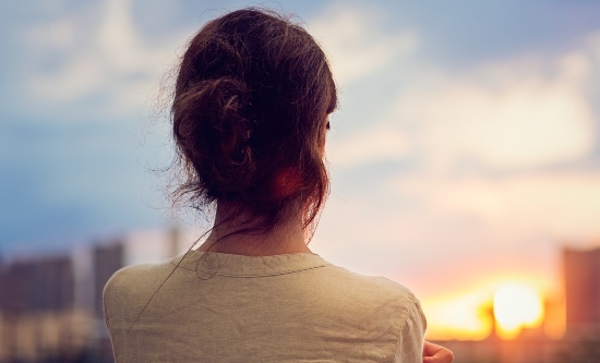 Woman with back to the camera looking into the distance to a city landscape