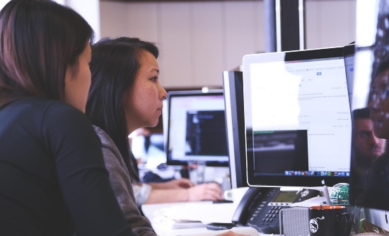 Two women concentrating on a computer screen in an office environment