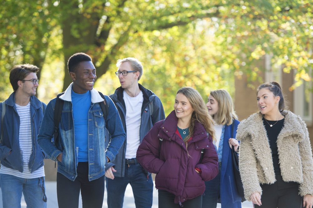 Mixed group of students walking outdoors, chatting and smiling