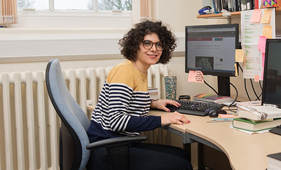 Female PGR student sitting at desk in front of computer screen