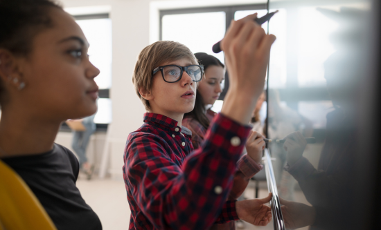 Boy with colleagues drawing on whiteboard