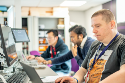 Associate Professor working at a laptop on a group project in the EEE Collaborative Teaching and Project Lab 1