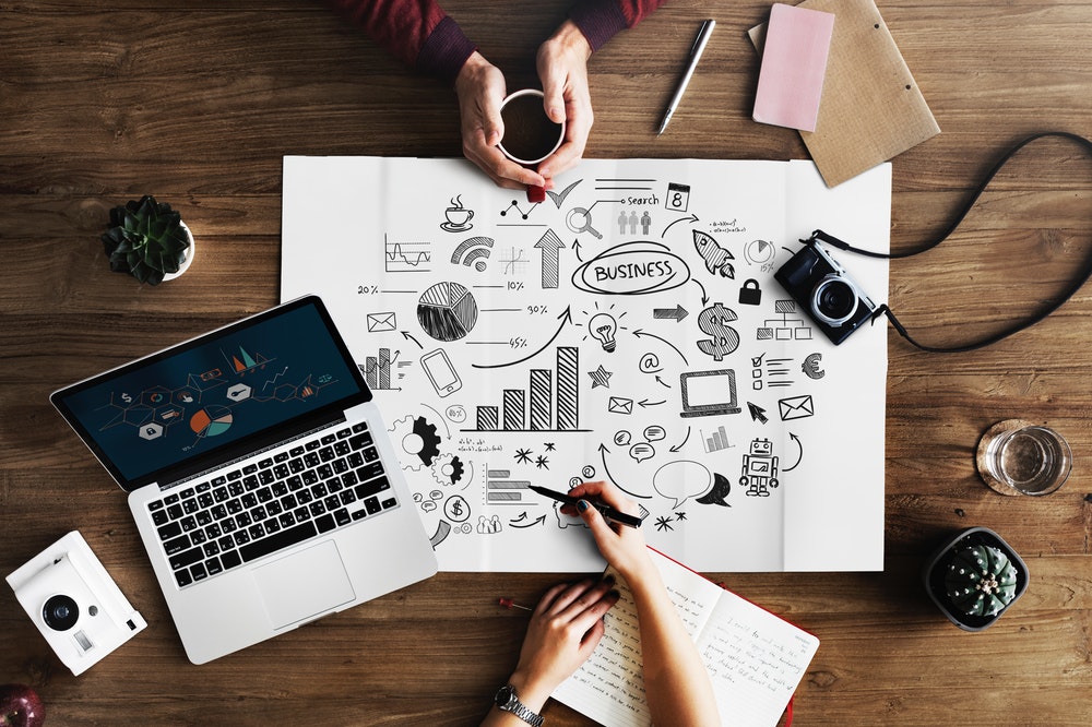 Flat lay Photography of Macbook Pro Beside Paper with business graphs