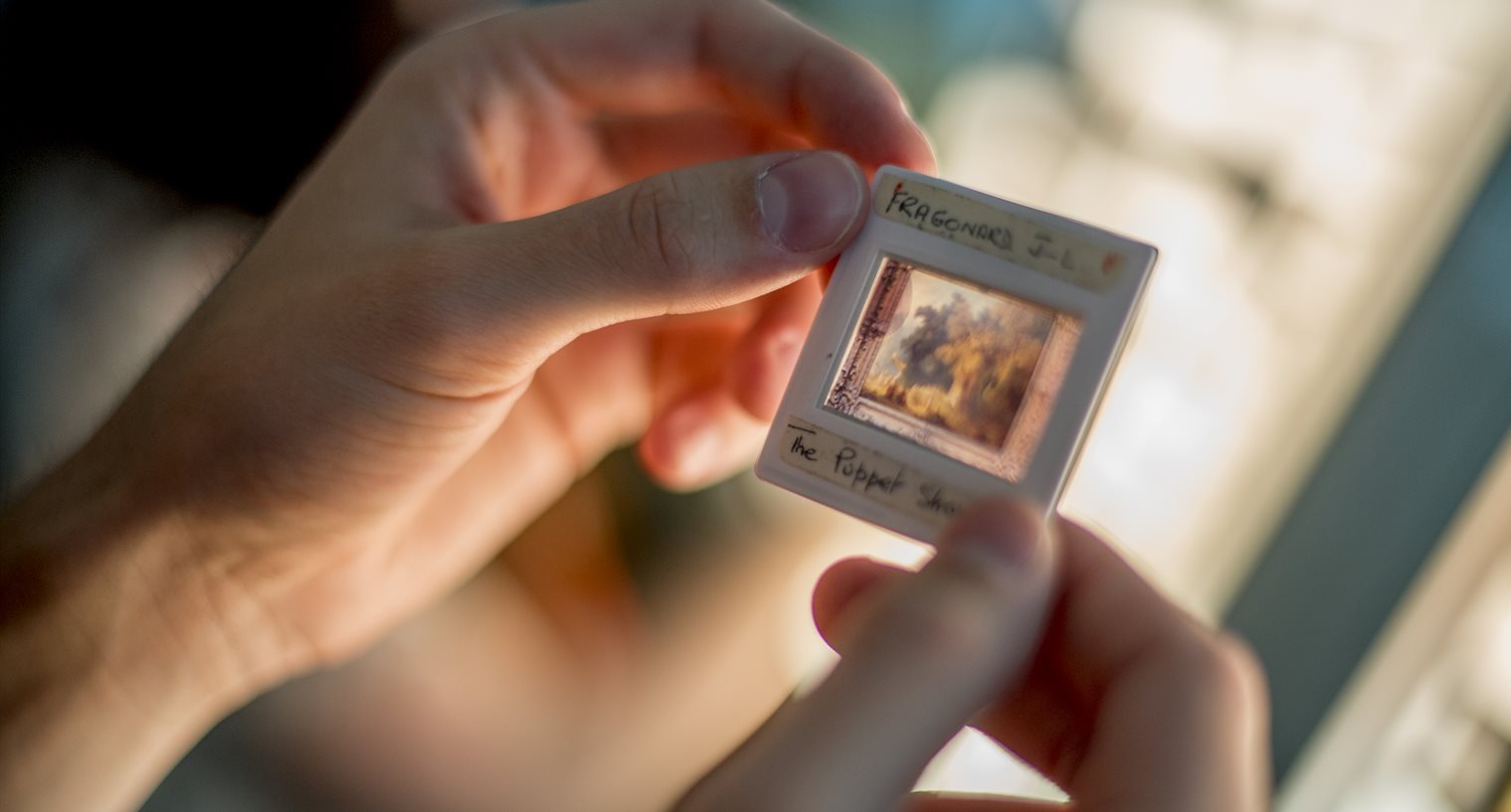 Student holding a photographic slide between their fingers over a light box
