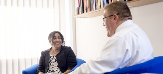 Two senior members of staff sitting in an office having a casual discussion
