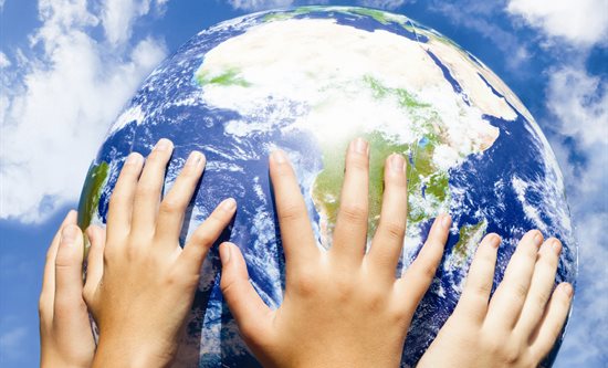 Group of hands holding globe up in the sky