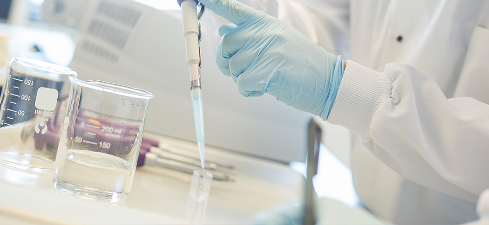 A researcher pipettes a liquid in one of our labs