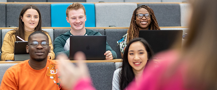A group of students with their laptops enjoying a lecture in a lecture theatre