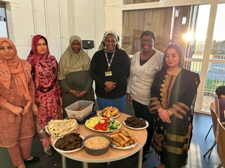 A group  of women standing round a table of different meals