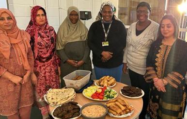 A group  of women standing round a table of different meals