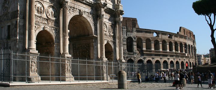 Arch of Constantine on a sunny day with Colosseum in background and crowds of people to the right of the photo