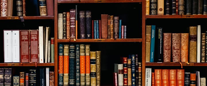 Dark wood bookshelves filled with a range of colourful old books (photo)