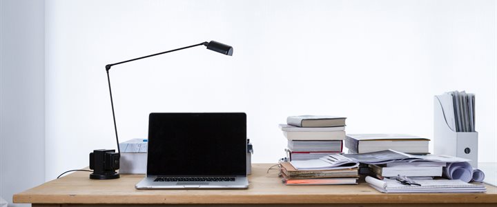 Pine desk with books, papers and open laptop