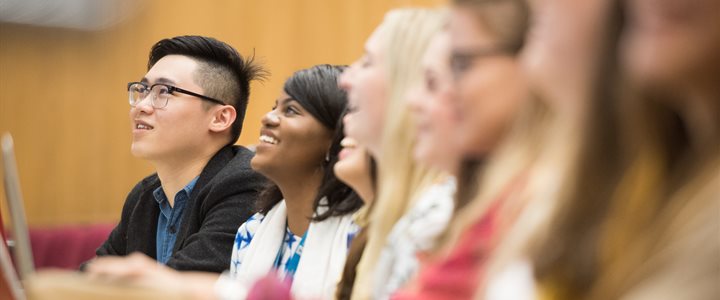 Diverse row of undergraduate students in a lecture looking up at an off-screen speaker