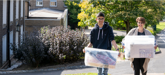 Students carrying moving boxes on campus
