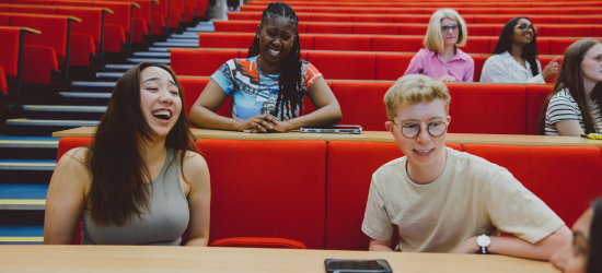 Students laughing together sat in a lecture theatre