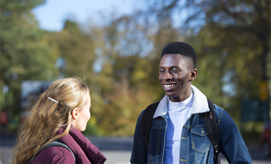 Two students standing outside talking and smiling